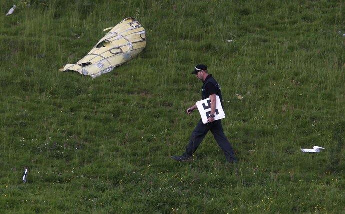 A police officer inspects a field after a mid-air collision between two aircraft