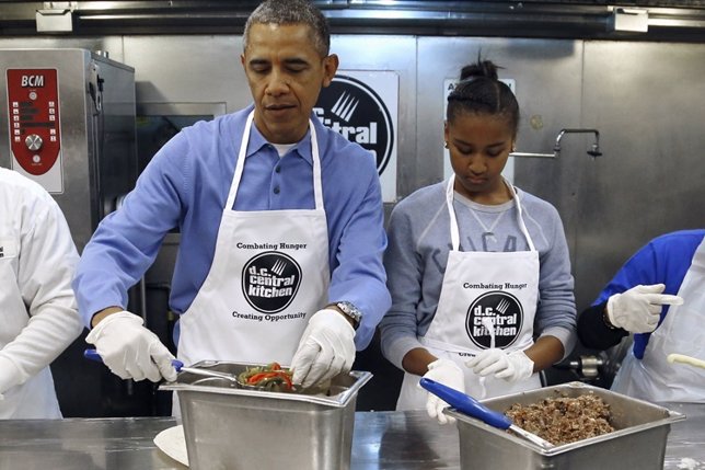 U.S. President Barack Obama (2nd L) and his daughter Sasha (2nd R) fill burritos