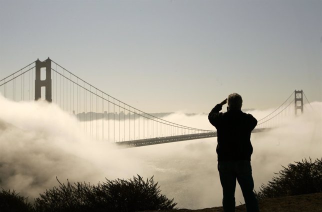 Man takes photographs of Golden Gate Bridge shrouded in fog in San Francisco