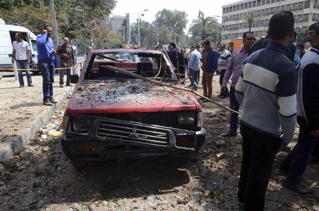 Gente cerca coche dañado por la explosion en la universidad de Egipto