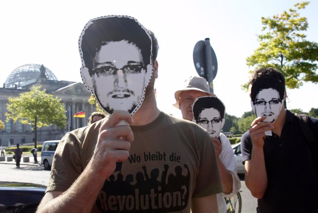 Protesters hold masks depicting former U.S. National Security Agency contractor 