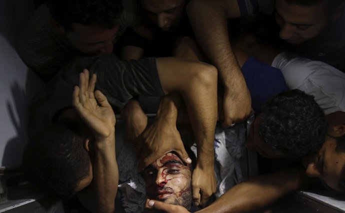 Personas se acercan al cuerpo de un militante palestino en Gaza