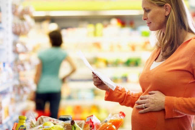 Embarazada en el supermercado buscando comida sana