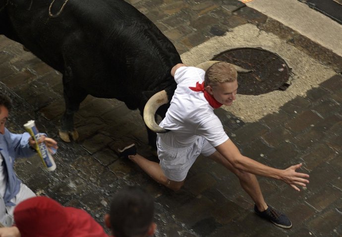 A runner is caught between the horns of a Fuente Ymbro fighting bull on Santo Do