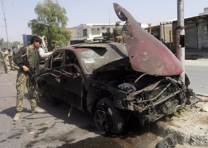 A member of the Afghan security force looks into a car, which was damaged after 