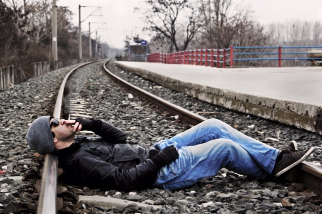Un hombre fumando sobre la vía de un tren