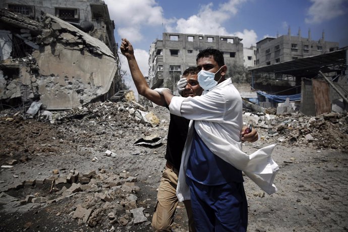 Un  médicu ayuda a un palestín nun bombardéu.