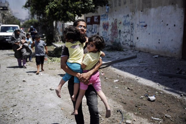 Un hombre palestino carga con dos niñas durante la ofensiva de Isarel sobre Gaza