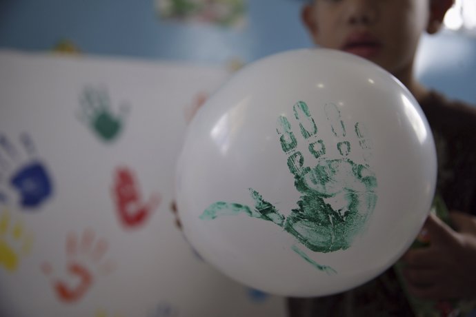 Un niño juego con un globo que lleva su mano pintada
