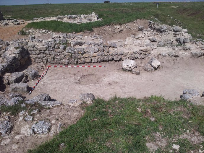 Un arqueólogo limpia los restos de un suelo de piedra
