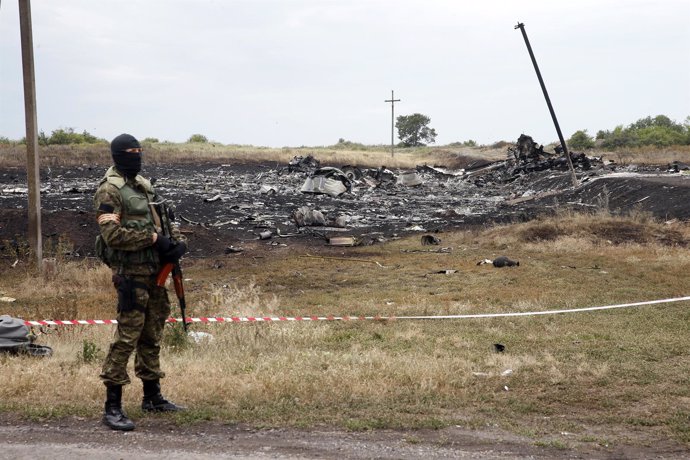 Pro-Russian separatist stands near a body at the crash site of Malaysia Airlines