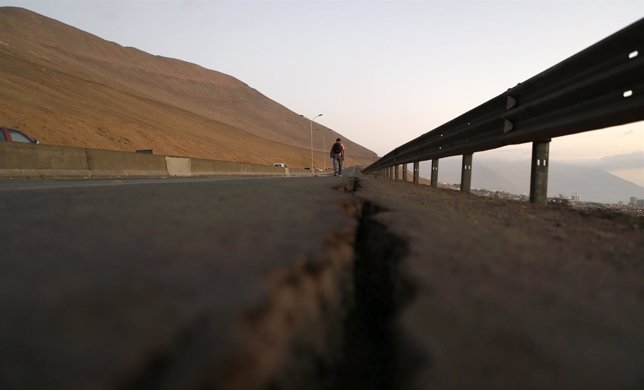 A resident walks along a damaged road after an earthquake and tsunami hit the no
