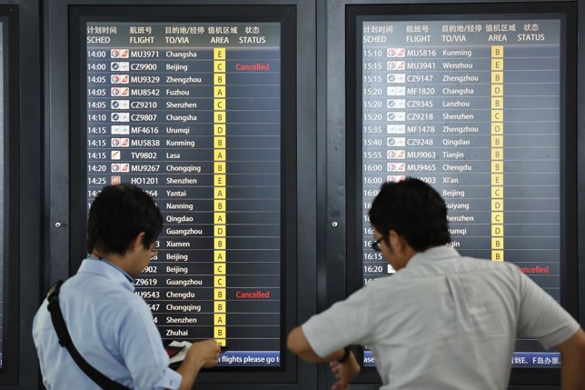 Pasajeros mirando una pantalla electrónica de un aeropuerto antes de su viaje
