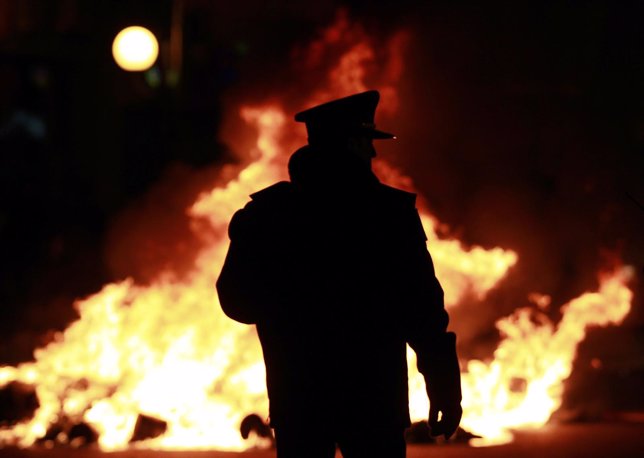 Policeman stands in front of bonfire lit by River Plate's soccer fans after thei