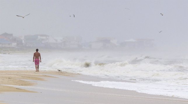 ST GEORGE ISLAND, FL - JUNE 6:  6:  A man walks on the beach in the heavy rain a