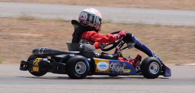 Un niño en un kart competición deportes coche master casco karting