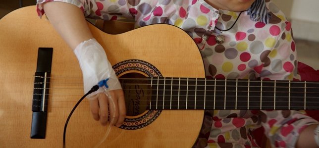 Niña enferma tocando la guitarra