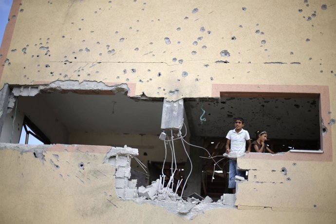 Palestinos miram a través de un agujero abierto por un proyectil