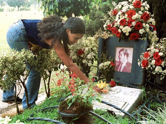 Una mujer pone flores en la tumba de Pablo Escobar