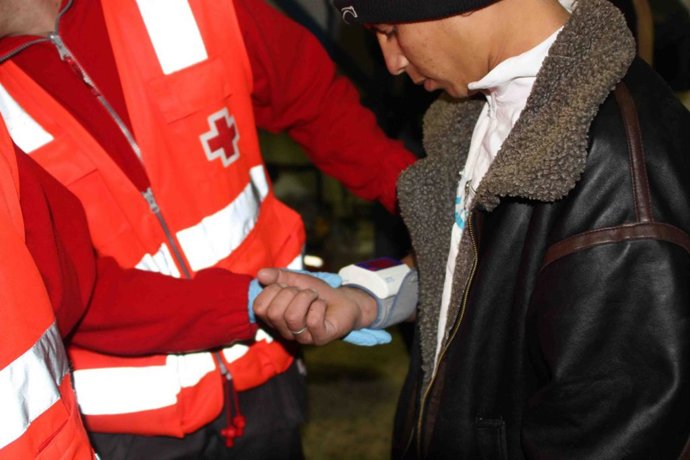 Un voluntario atiende a un inmigrante acabado de llegar
