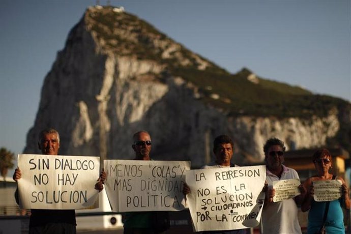 Trabajadores españoles posan para una fotografía mientras sostienen letreros fre