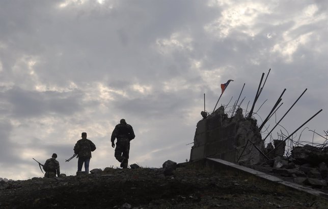 Pro-Russian separatists walk at a destroyed war memorial on Savur-Mohyla, a hill