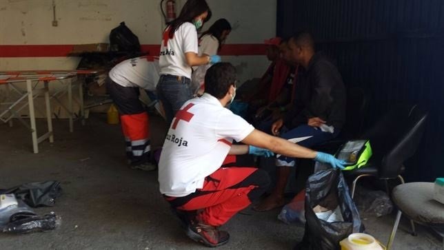 Miembros de la Cruz Roja atienden a inmigrantes llegados a España en una patera