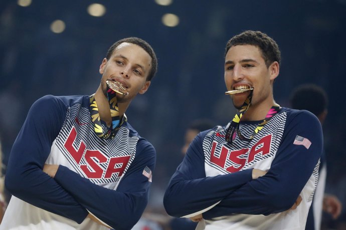 U.S. Players Stephen Curry (L) and Klay Thompson bite their gold medals after wi