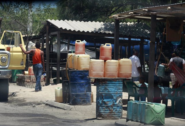 People stand near containers of smuggled petrol placed along a roadside in Cuest