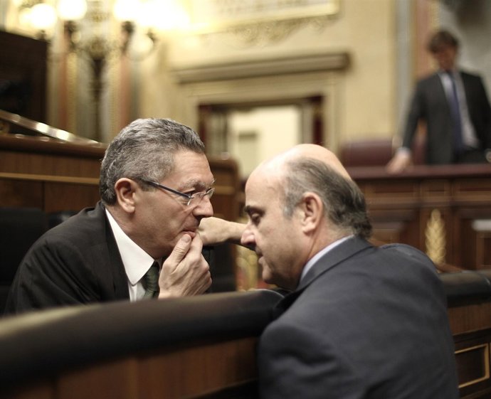Alberto Ruiz Gallardón y Luis De Guindos hablando en el hemiciclo