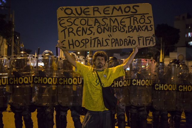 A protester stands in front of riot police during a demonstration in Rio de Jane