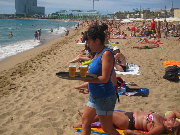 Una camarera sirve bebidas hasta línea de agua en un chiringuito de Barcelona