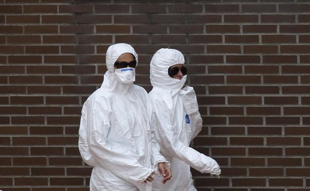 Trabajadores cerca de la casa de la enferma con ébola