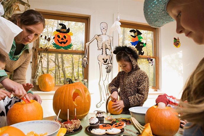 Woman and kids carving pumpkins