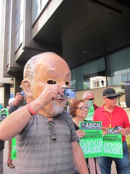 Un manifestante porta un 'cabezudo' de Rato frente a la sede de Bankia