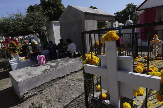 A family eats a meal on the grave of a relative at the municipal cemetery, durin