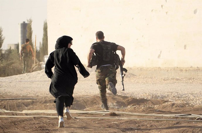 Un reportero corre con una combatiente rebelde en Alepo 