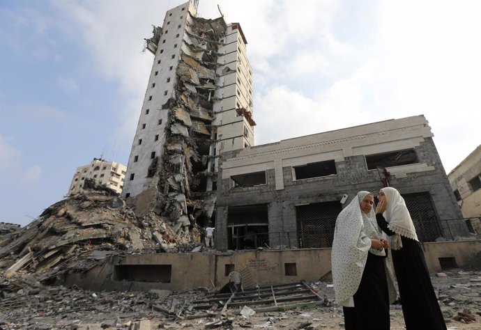 Mujeres palestinas junto a una torre bombardeada en Gaza
