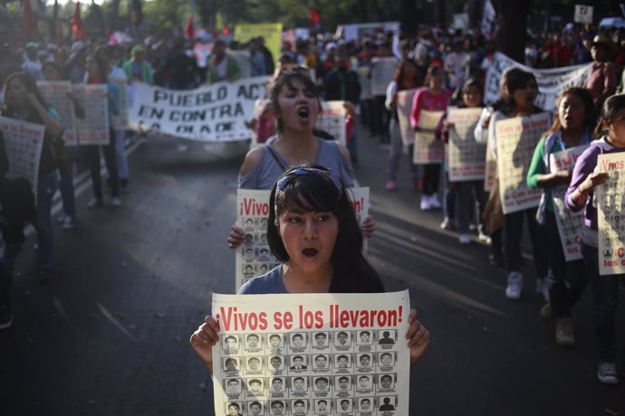 Women shout slogans and hold posters with pictures of the 43 missing students fr