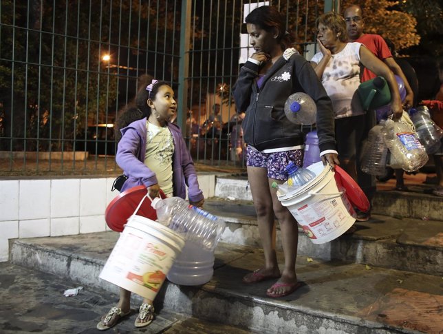 Residentes de Cantareira hacen fila para llenar cubos de agua en Brasil.