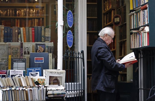 A man reads a book outside an antique bookshop in central London
