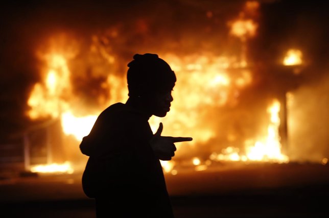 Un hombre frente a edificio en llamas durante disturbios en Ferguson