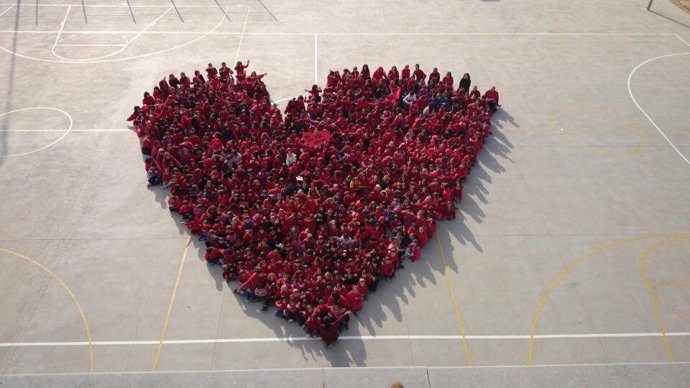 Alumnos y profesores formando un corazón en el patio del colegio