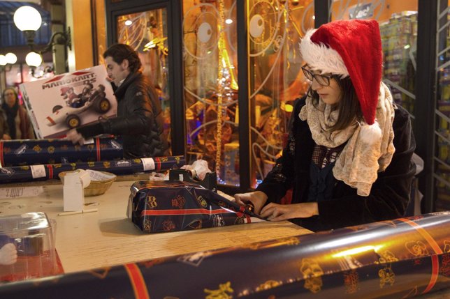 A young women gift wraps a package at the Village of Paris JoueClub toy shop
