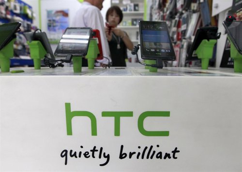 Un grupo de clientes observan unos teléfonos de la firma HTC en una tienda