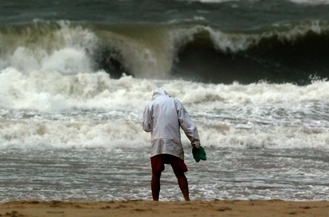 Un hombre frente a una ola generada por un tifón.