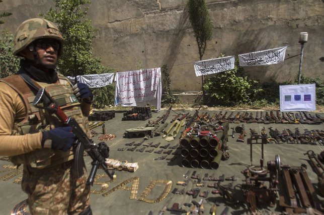Un soldado posa al lado de munición y armamento requisado a fuerzas talibanes.