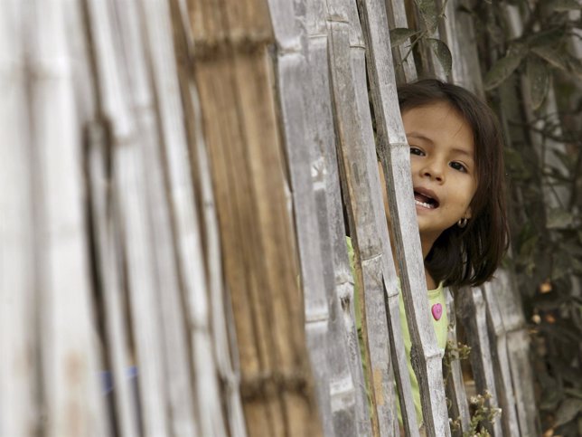 Una niña mira a través de una valla en El Recreo , cerca de Guayaquil 