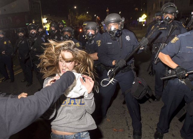 A protester flees as police officers try to disperse a crowd comprised largely o