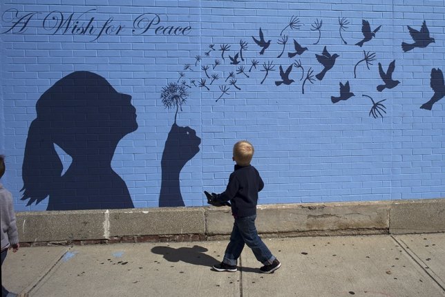 Un niño mira un mural que tienen un mensaje de paz